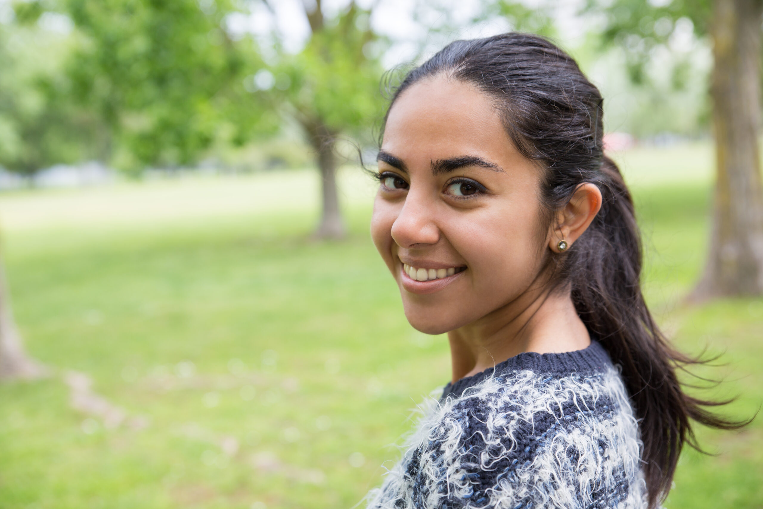happy pretty young woman posing at camera in park